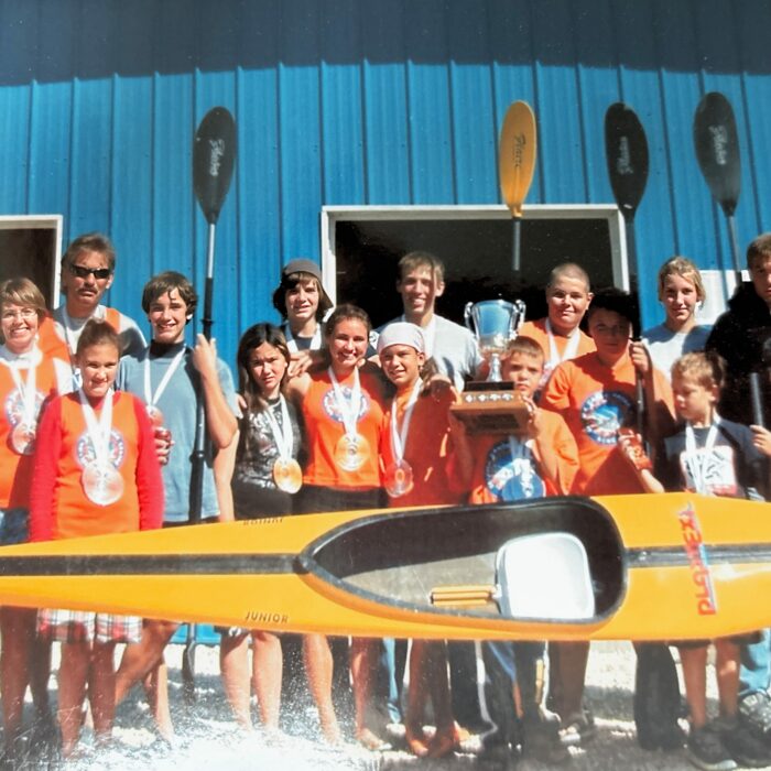 Selkirk Canoe Kayak Centre Recieve $2200 For the Purchase of Two Mini Canoes, 2008, Selkirk District Community Foundation A group of young adults stand outside a blue building. They are holding a yellow kayak and paddles