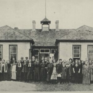 A black and white photo of South Ward School. Teachers and students stand outside the front of the school for the photo