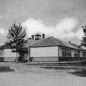 A black and white photo of South Ward school from an angle. There are trees on either side of the school