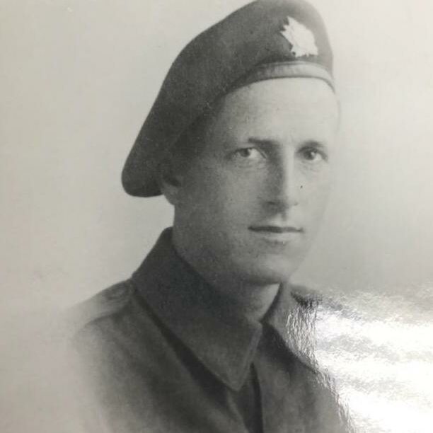 Black and white photo of a man in military uniform. He is wearing a hat and looks directly at the camera