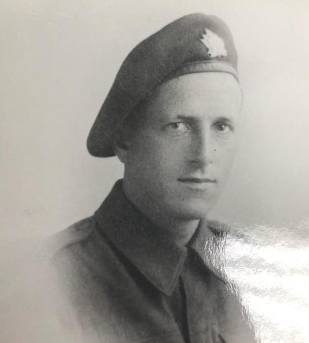 Black and white photo of a man in military uniform. He is wearing a hat and looks directly at the camera