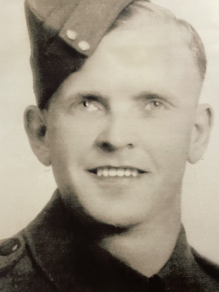 Black and white picture of a man in military uniform. He smiles at the camera
