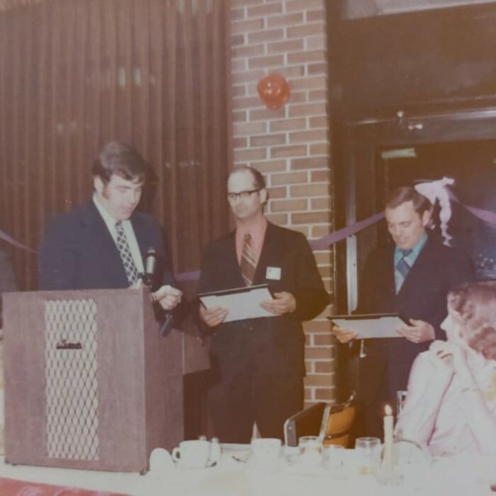 Colour image of a group of men around a podium