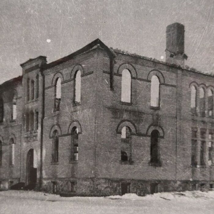 Central School the Morning After the Fire, 1906, Joen Hadfield A black and white photo of a large school building which has just experienced a fire. On the left side of the building is a dark area showing soot from the fire