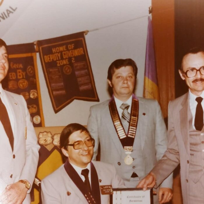Colour image of a group of men wearing medals and holidng a certificate