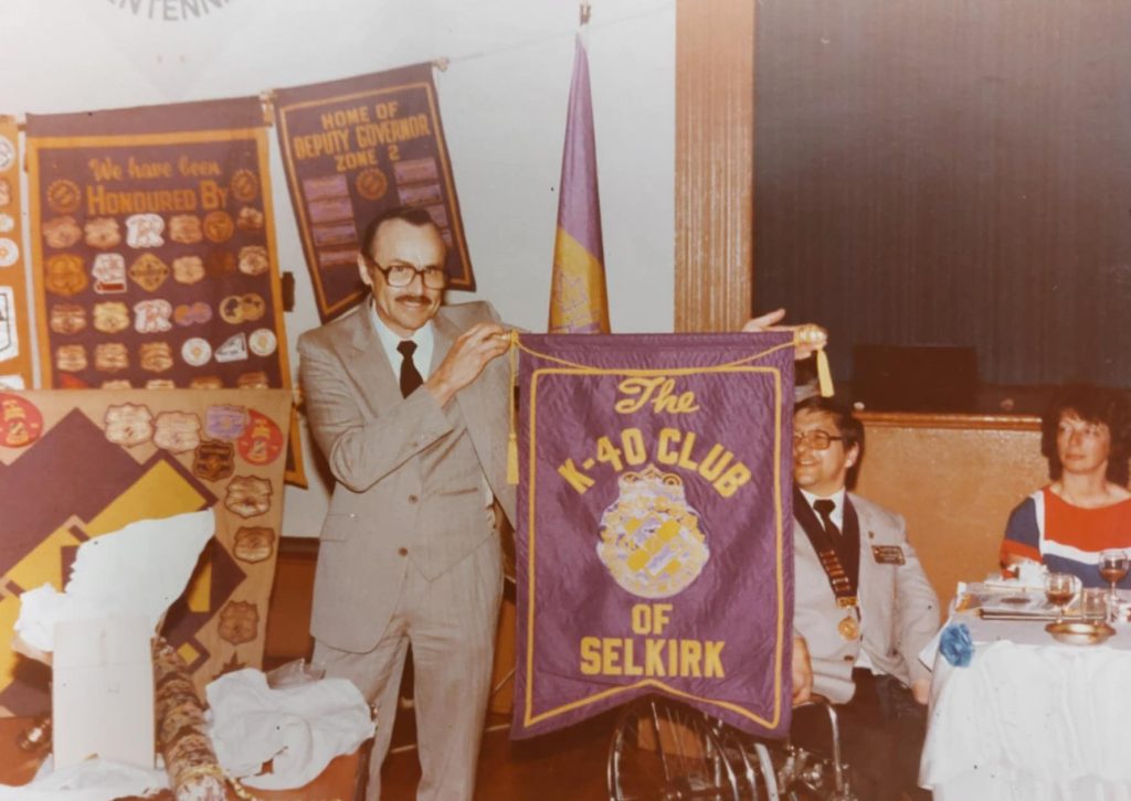 A colour image of w man holding up a K-40 Club banner
