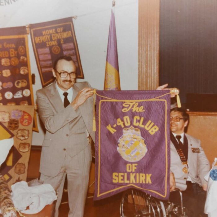 A colour image of a man holding up a K-40 Club banner
