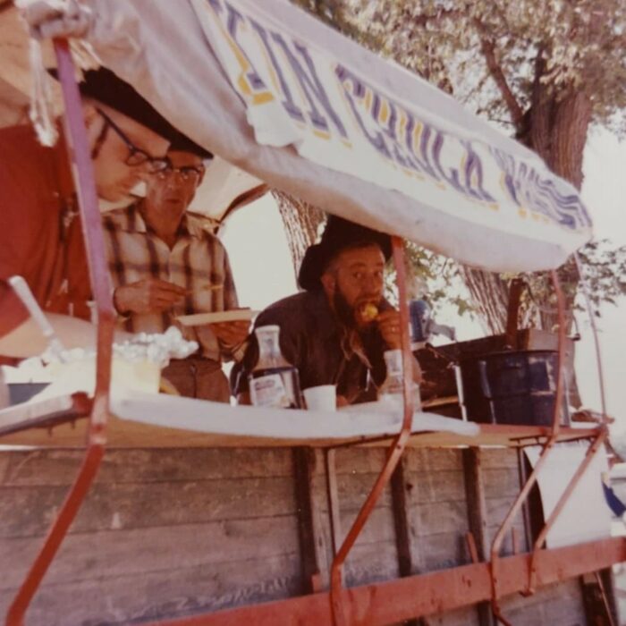 A colour image of three men standing serving food.