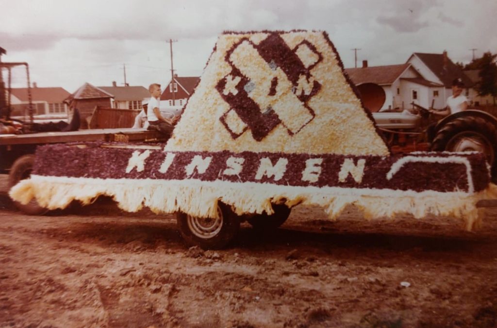 A colour image of a parade float. The flowers on it that spell 'Kinsmen'