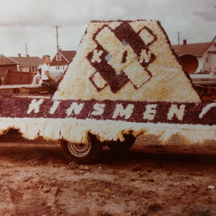 A colour image of a parade float. The flowers on it that spell 'Kinsmen'