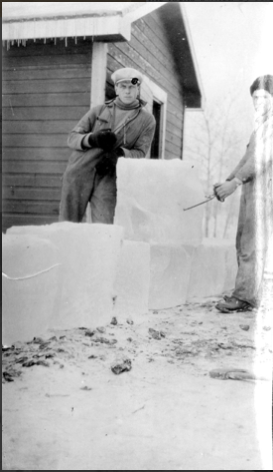 A black and white image of men standing beside large blocks of ice. One holds an ice pick which clamps the ice for lifting