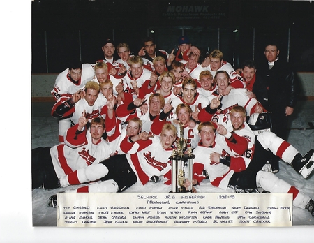 A colour image of a group of hockey players surrounding a trophy. Some are laying on the ice