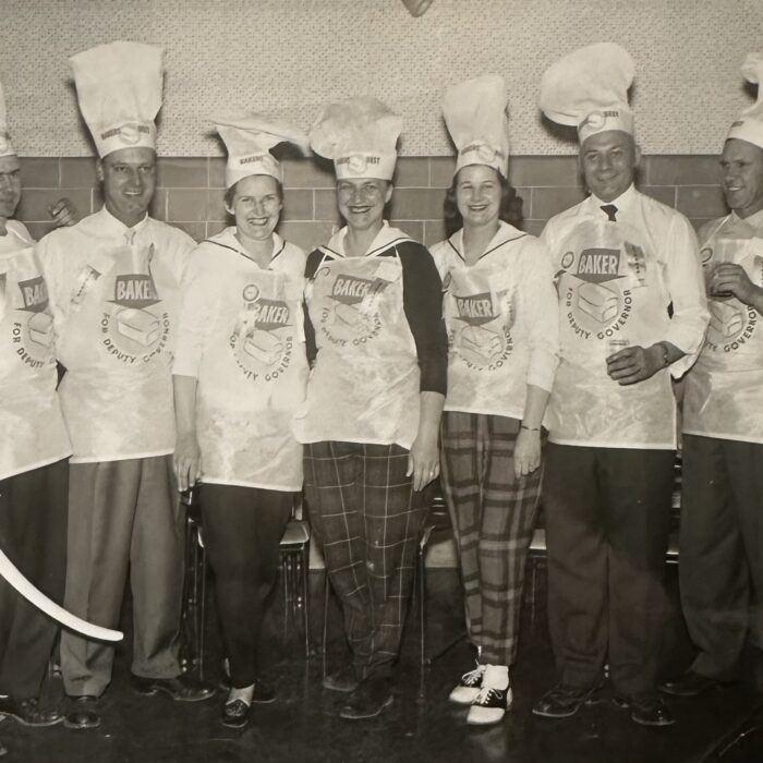 A black and white image of a group of men and women wearing chef hats and aprons