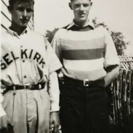 Charles Griffiths, c1940, Canadian Virtual War Memorial A black and white image of two young men standing looking at the camera. The young man on the right wears a wide-striped shirt and black pants. His hands are in his pockets. The young man on the left wears a baseball style button up shirt with the words "Selkirk" across the front.