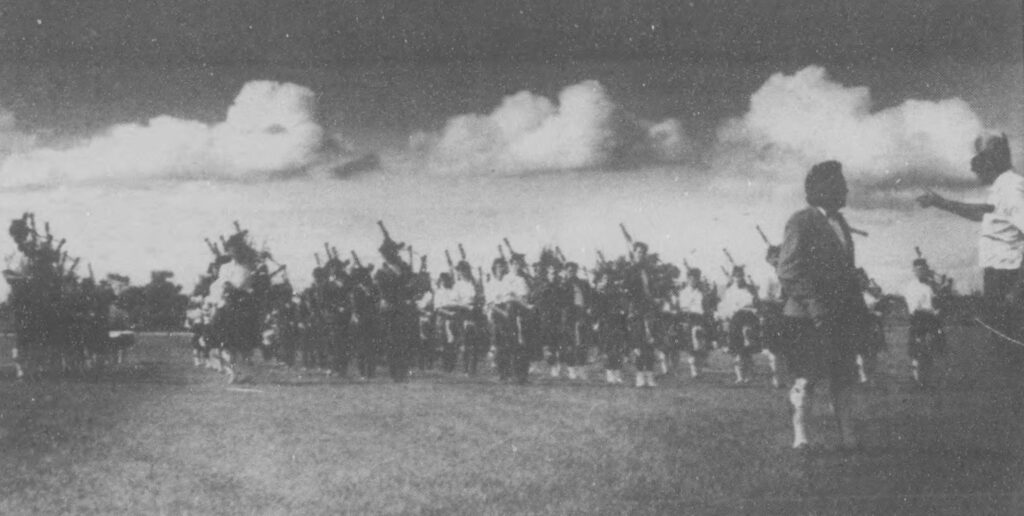Black and white image of bagpipe players gathered together in a march