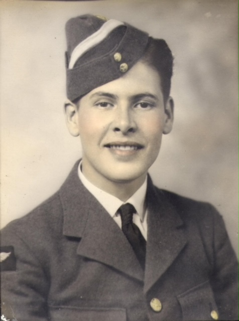 A black and white image of a young man in military uniform. He looks at the camera and smiles