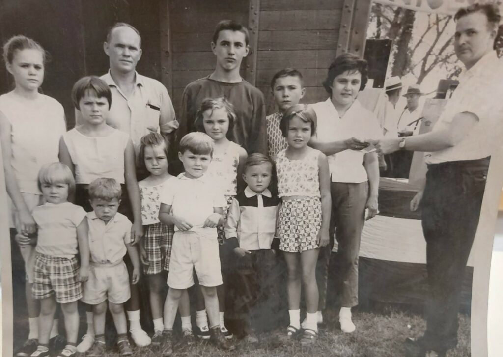 Black and white image of a large family of children. Their father is at the back left