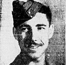 Black and white image of a young man in military uniform. He looks to the left of the camera and smiles