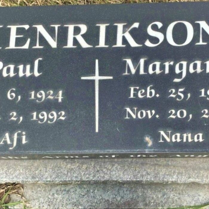 A colour image of a gravestone. The gravestone is grey with white lettering