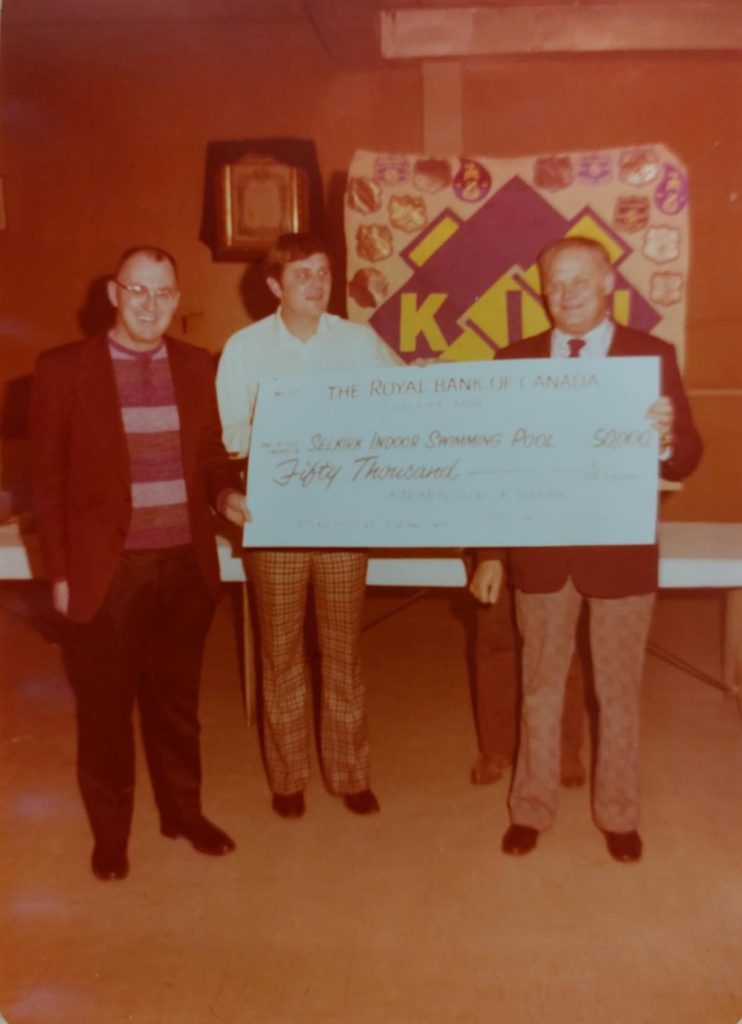 Colour image of three men standing behind a large cardboard cheque