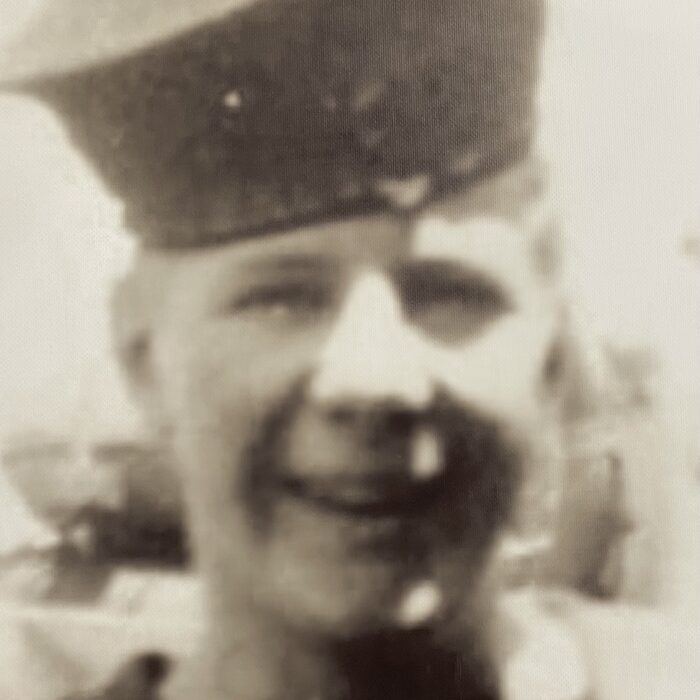 Black and white image of a young man in military uniform. He looks and smiles at the camera