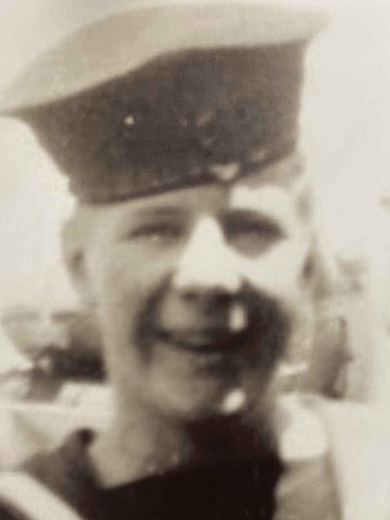 Black and white image of a young man in military uniform. He looks and smiles at the camera