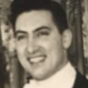 Black and white image of a young man. The photo is taken from the neck up and the man is smiling