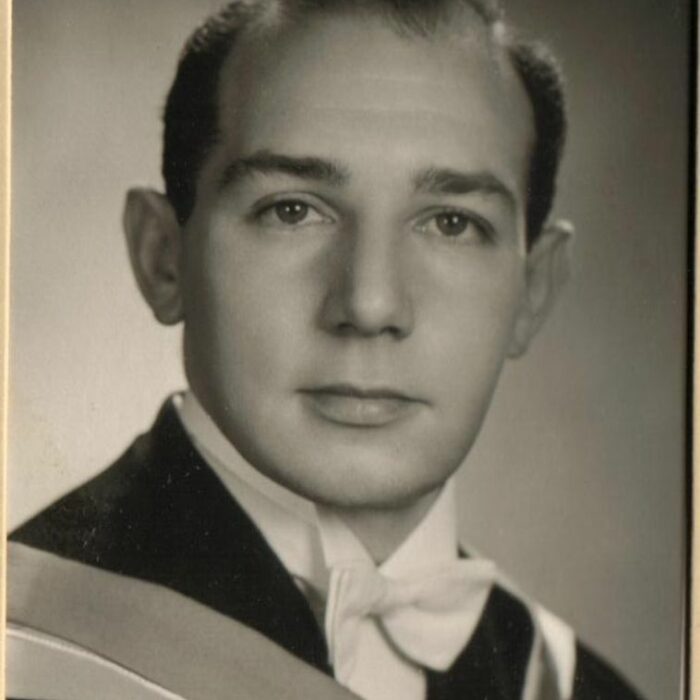 Black and white photo of a young man wearing a white tie and graduating robes. The young man looks slightly right of the camera