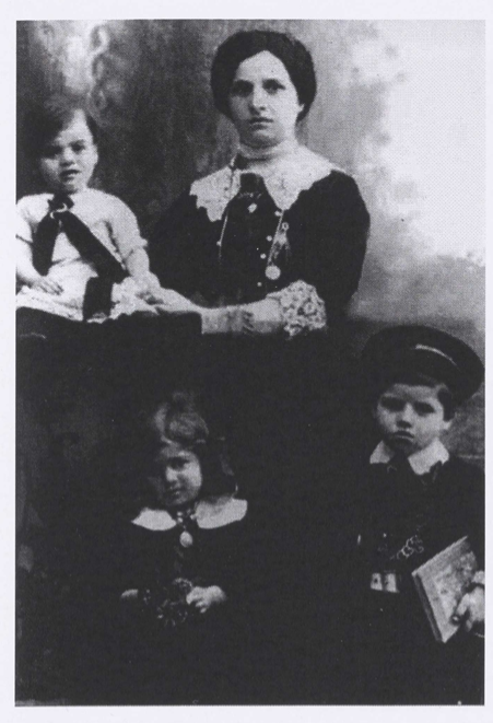 Black and white photo of a mother and three children. They are all dressed up in nice clothes with white collars