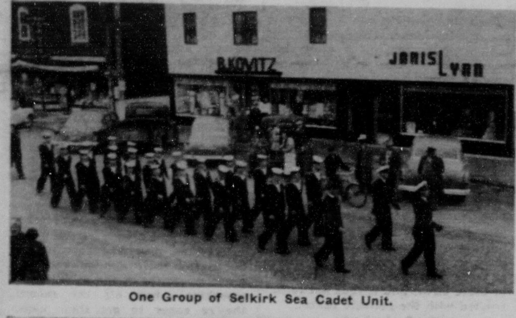 Selkirk's Sea Cadet Unit in the Coronation Parade. The photo is grainy, black and white and shows a parade procession coming down Manitoba Ave
