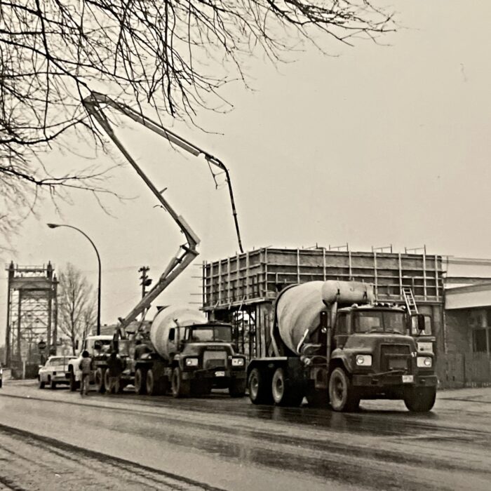 Construction of the Civic Office, 1983, Selkirk Enterprise Black and white photo of the construction of Civic Office. There is a large pump truck parked outside the building and a cement truck driving away down the road