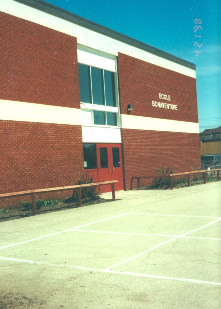 Colour photo of a brick building with white trim and red doors