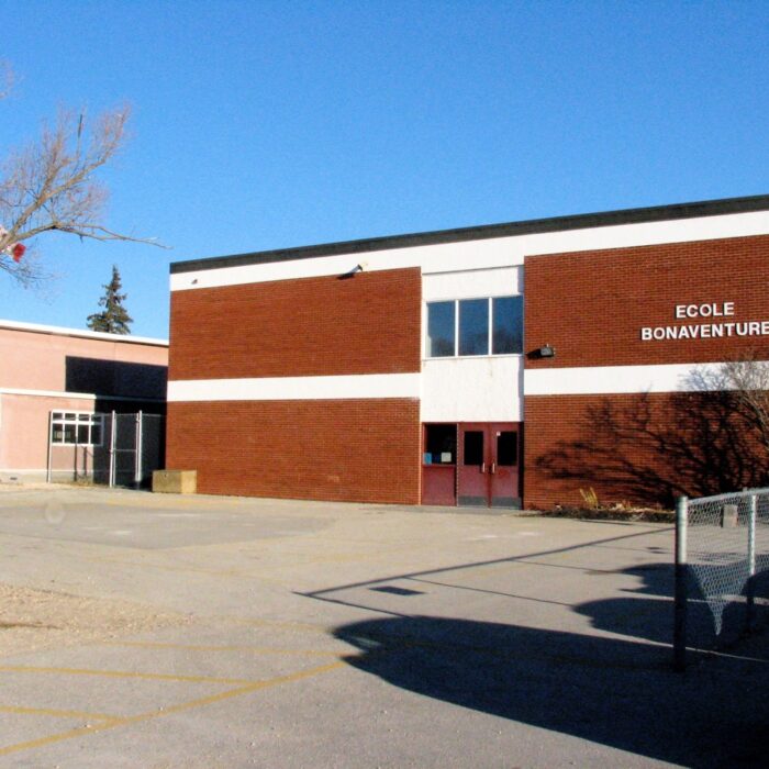 École Bonaventure with the West Wing Access, 2003, Cecile Barrett Colour photo of a brick building with white trim and red doors. The sky is blue in the background