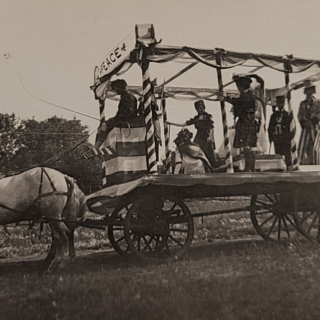 Horse Drawn Float, 1919, Selkirk Museum Collection Black and white photo of a horse drawn parade float. There are people standing on the back of the float