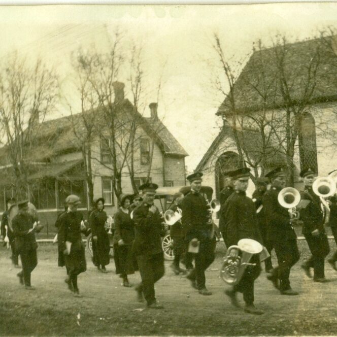 Marching Band Walking Down Eveline, 1919, Selkirk Museum Collection Black and white photo of a marching band walking down the street