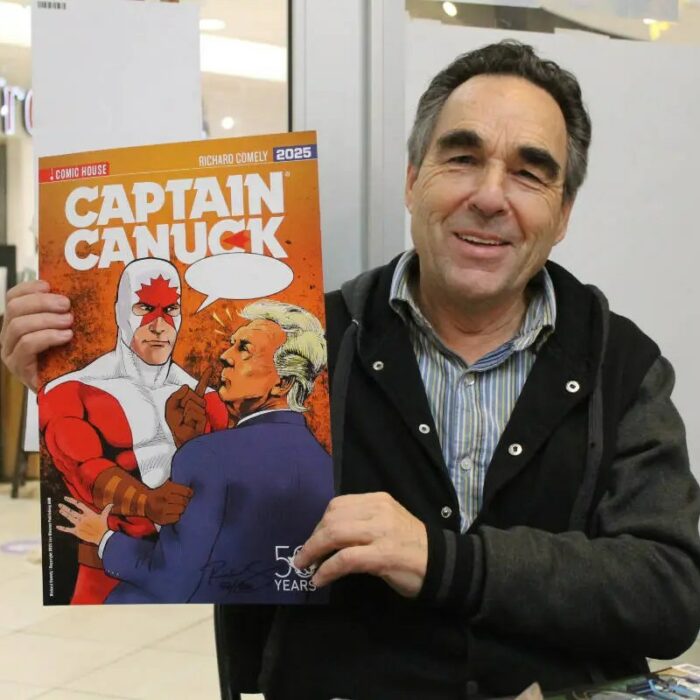 Colour photo of Richard Comely holding a comic book and smiling at the camera