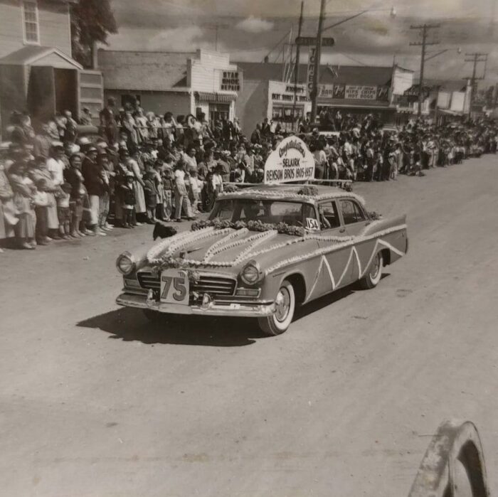 Selkirks 75th Parade Benson Bros, 1957, Selkirk Museum Collection Black and white colour of a decorated car driving down the road in a parade. The sign on the car reads Benson Bros.