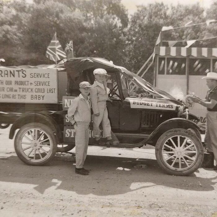 Selkirks 75th Parade Car, 1957, Selkirk Museum Collection Black and white photo of an old truck decorated for a parade. There are two young boys standing in front of the vehicle.