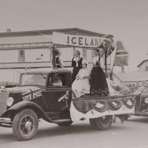 Selkirks 75th Parade Icelandic, 1957, Selkirk Museum Collection Black and white coloured photo of a vehicle decorated for a parade. There are people standing in the back of the truck with a banner which reads 'Icelandic' above them