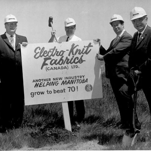 Electro-Knit, 1968-1979, Winnipeg Tribune Black and white photo of a group of men wearing hard hats holding a sign for Electro-Knit