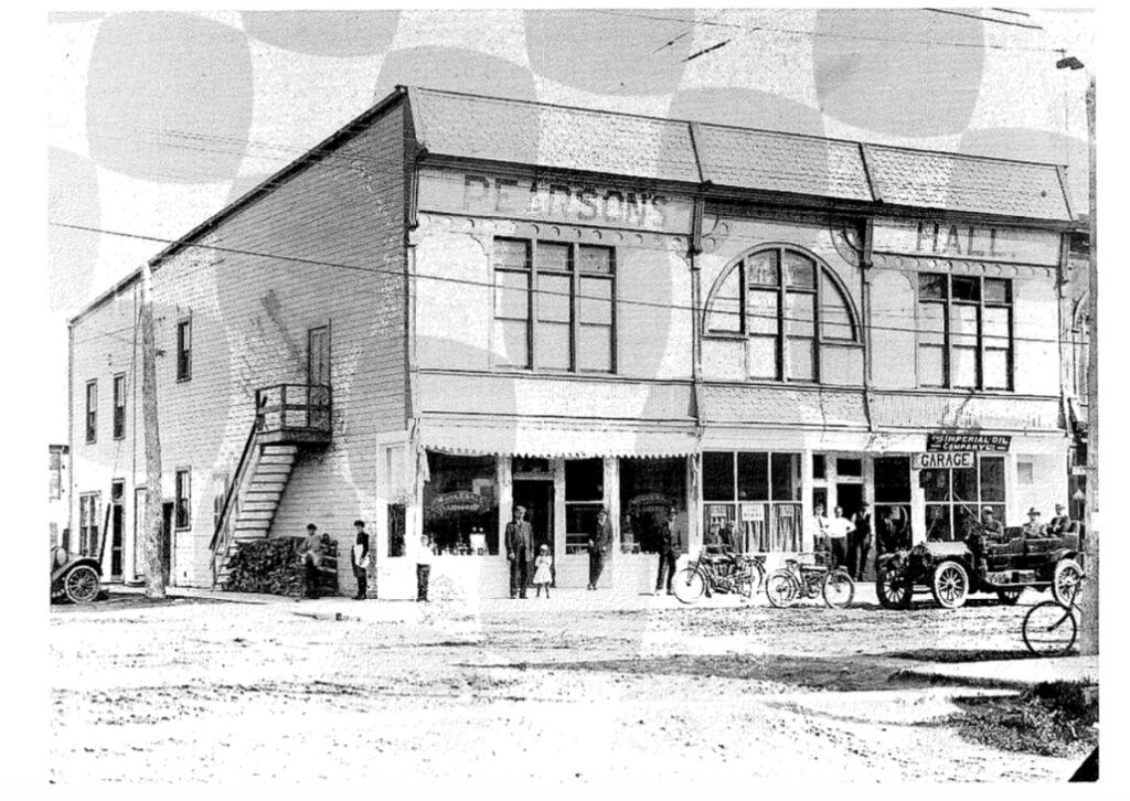 Black and white photo of a two story building with the letters 'Pearsons Hall' written across the front. There is an arched window at the center
